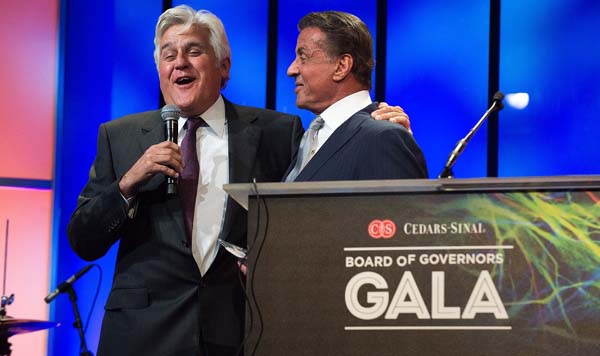 Jay Leno and Sylvester Stallone share a laugh on stage